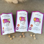 Three Gogoma freeze-dried treats pouches on a concrete surface with a dog's paw in the background.