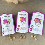 Three Gogoma freeze-dried treats pouches on a concrete surface with a dog's paw in the background.
